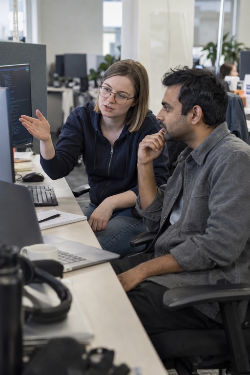 Two developers discussing code on a monitor in their office